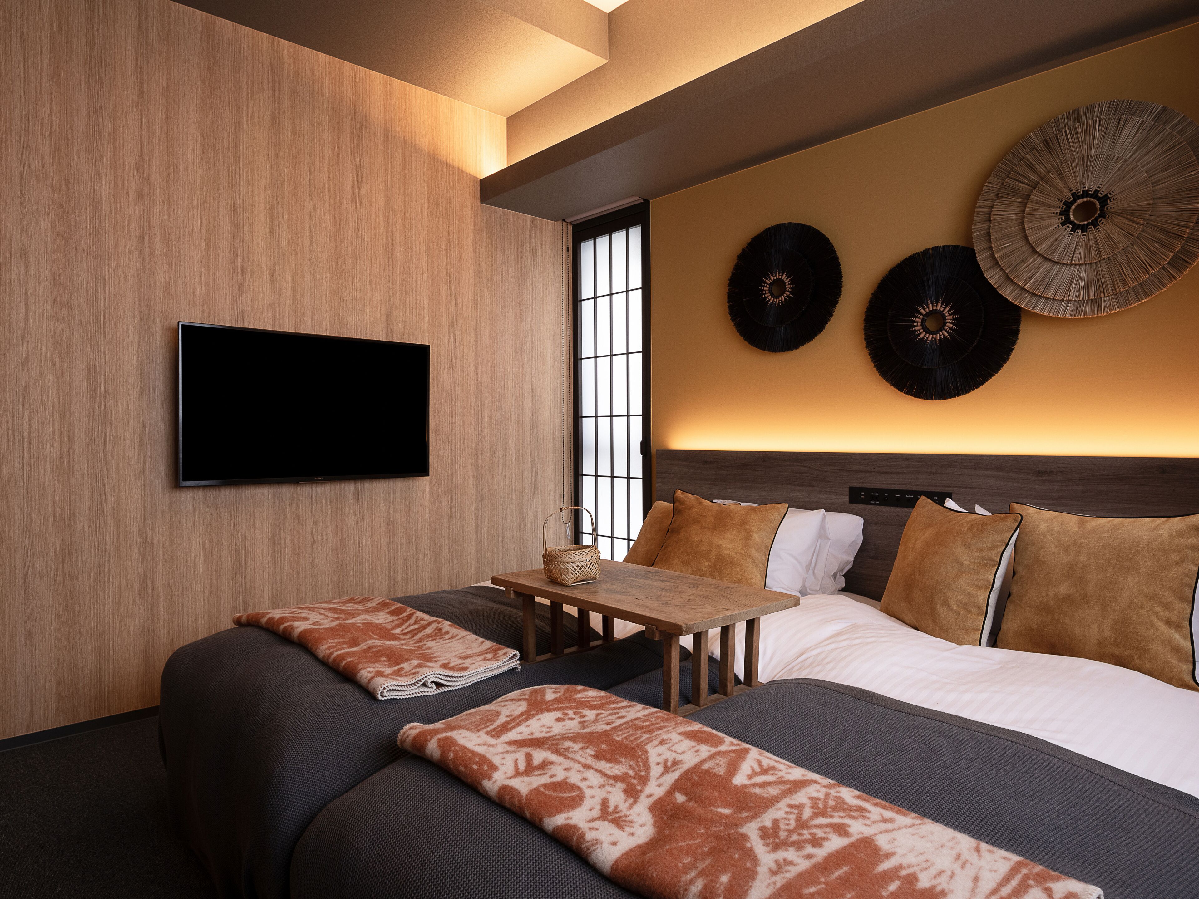 Ein modernes Hotelzimmer mit einem großen Bett, einem Flachbildfernseher, einem kleinen Tisch und Wanddekorationen.