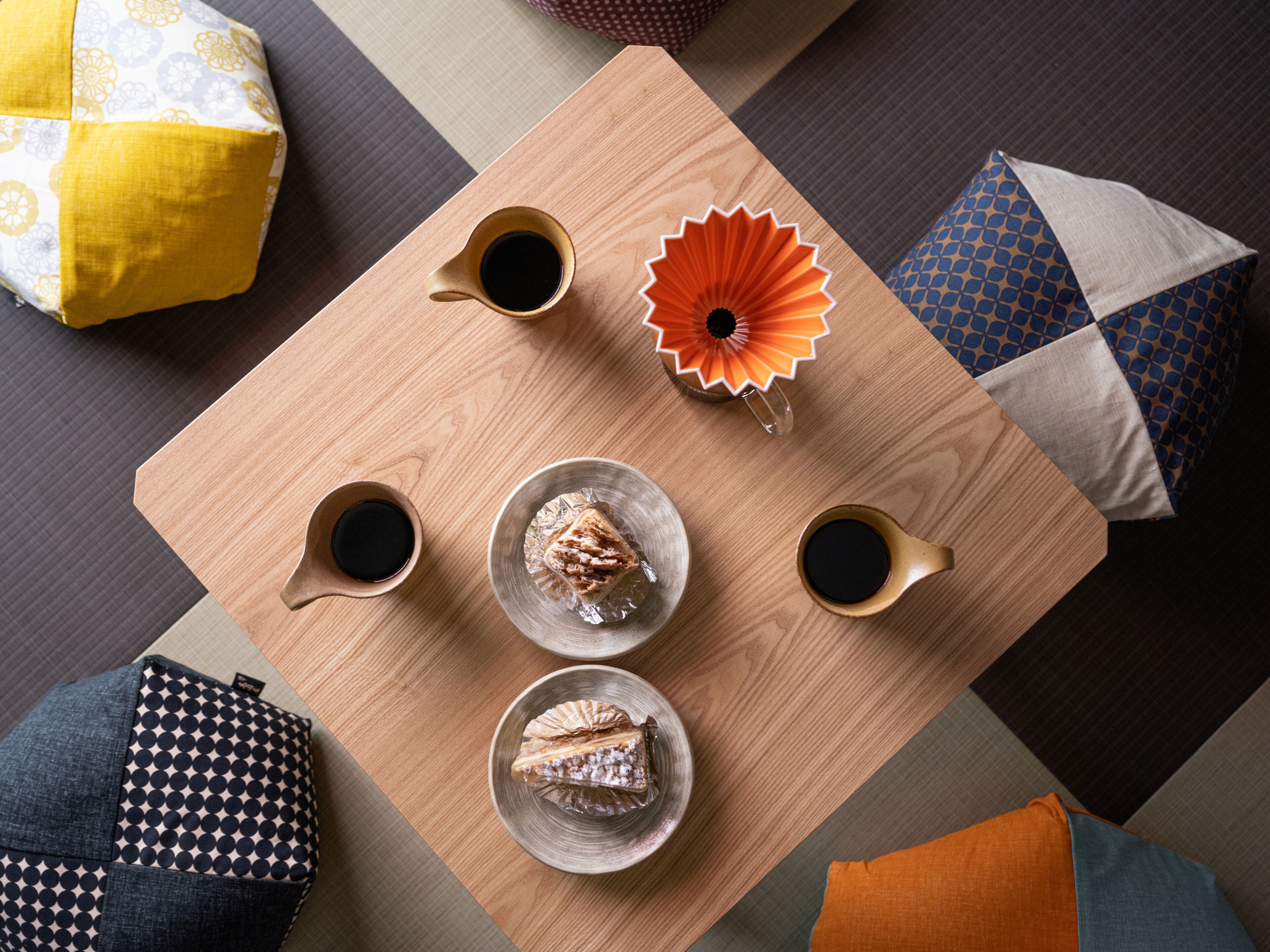 Una mesa de madera con dos tazas de café, una flor decorativa y dos platos con pasteles.
