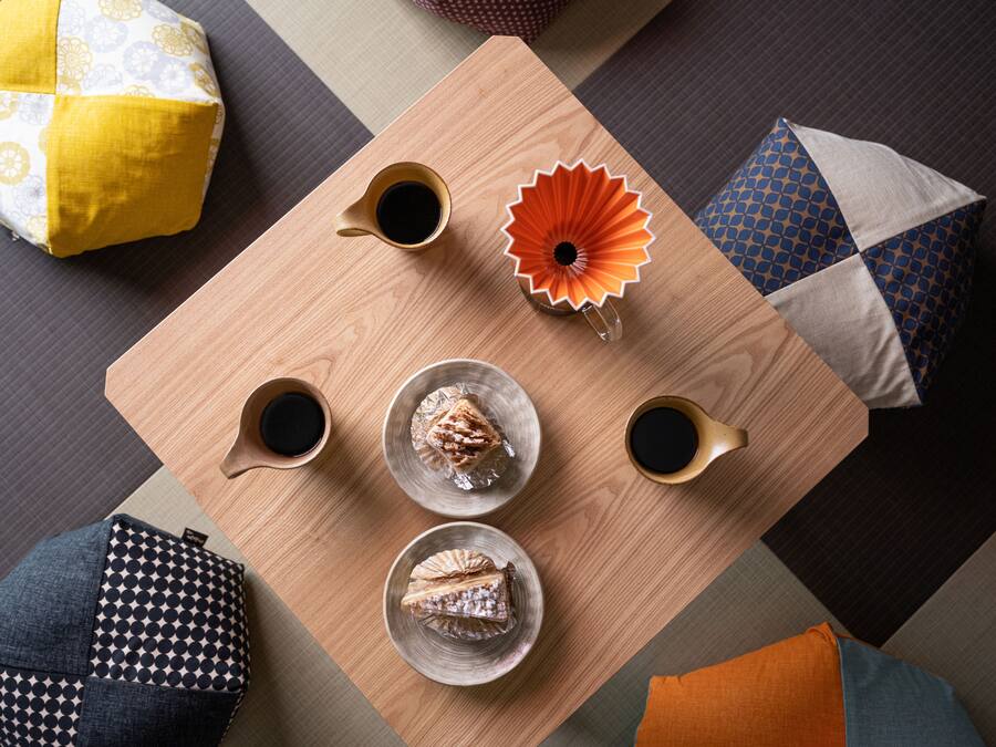 Una mesa de madera con dos tazas de café, una flor decorativa y dos platos con pasteles.