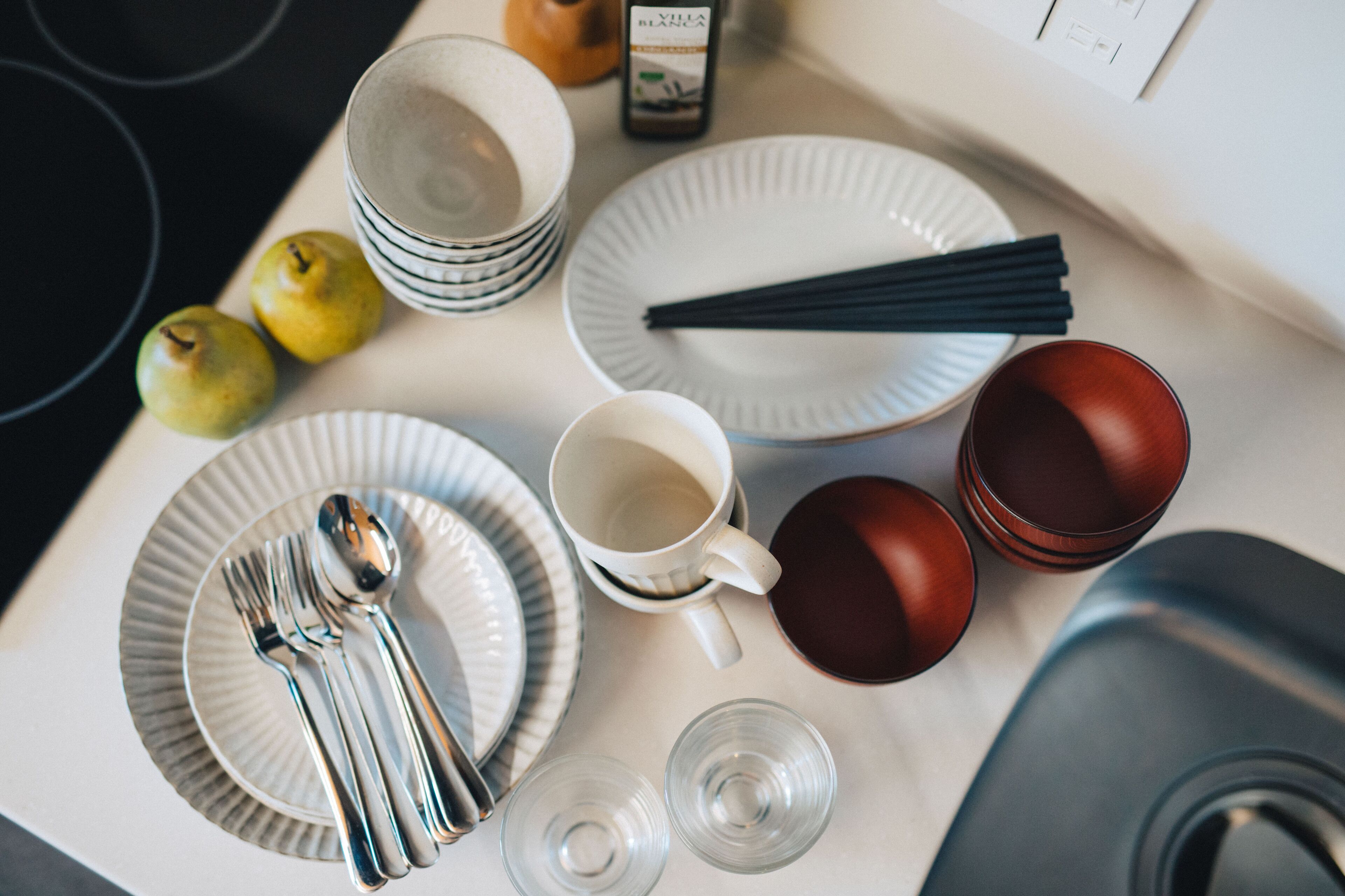 A dining table with plates, cutlery, glasses, and a bottle.