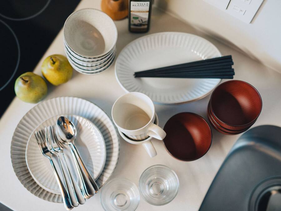 A dining table with plates, cutlery, glasses, and a bottle.