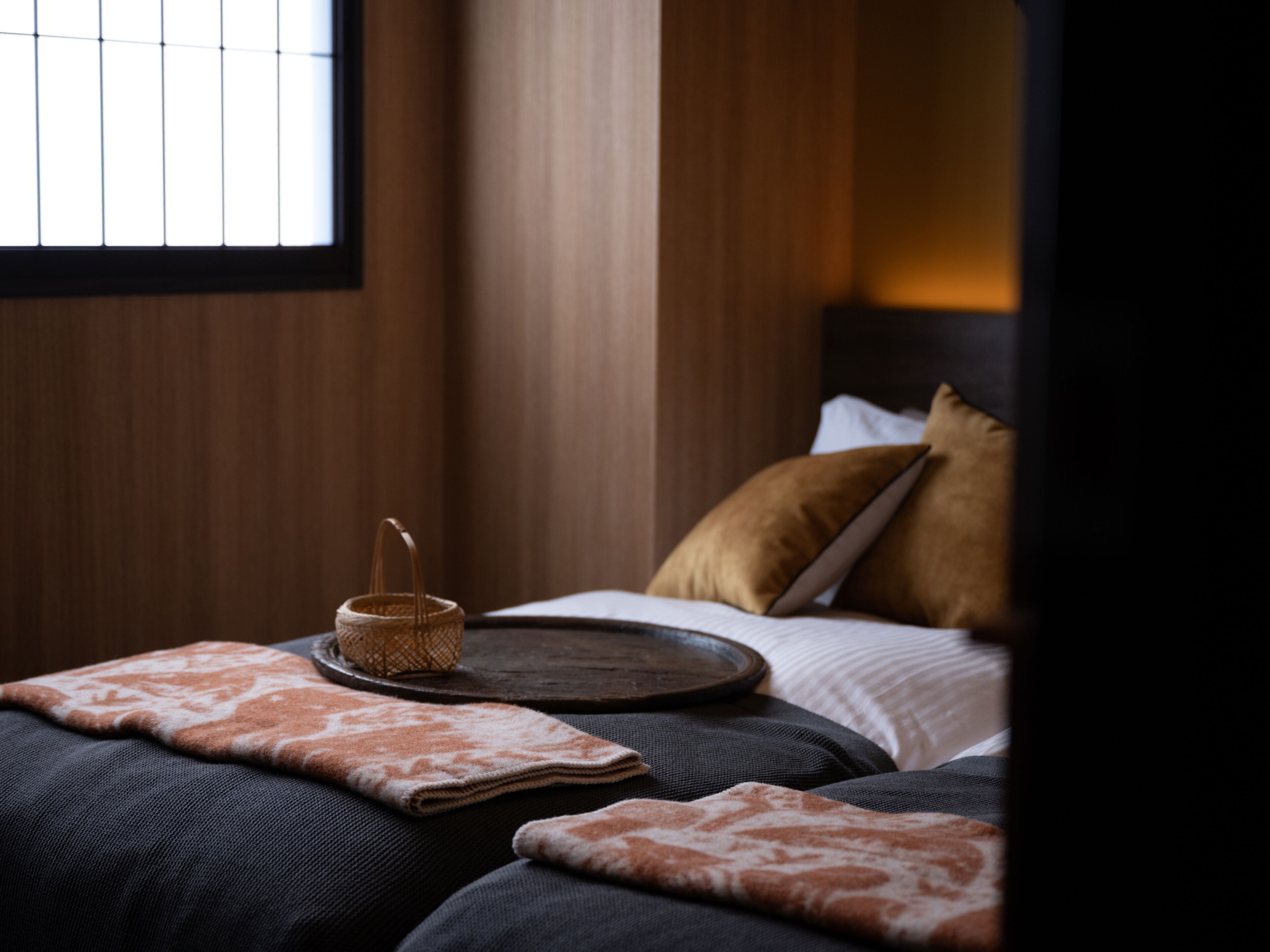 A neatly made bed with a tray, pillows, and a woven basket.