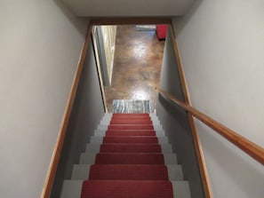 Stairs lead to an upper level with a landing and a red object at the top.
