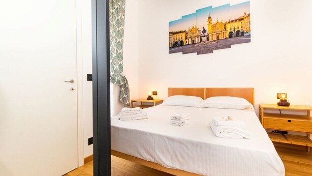 Ein Hotelzimmer mit einem Bett, zwei Nachttischen, einem Wandbild und einer Tür.