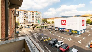 Straßenansicht mit einem großen Gebäude, das ein auffälliges 'M'-Logo, eine Fußgängerüberweg und parkende Autos zeigt.