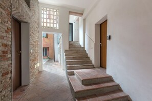 A staircase leading to a second floor, a door on the right, and a brick wall on the left.