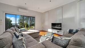 En moderne stue med et stort sofasæt, et glasbord og et fladskærms-tv.