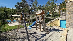 Une aire de jeux avec des balançoires, un toboggan et une structure d’escalade.