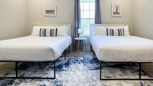 Ein Hotelzimmer mit zwei Betten, einem kleinen Tisch und einem Fenster mit Vorhängen.