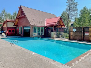 A building with a swimming pool, a red door, and a fenced area with warning signs. - Ski In - Ski Out. Perfect Location. Hot Tub. Pool. (Breckenridge)