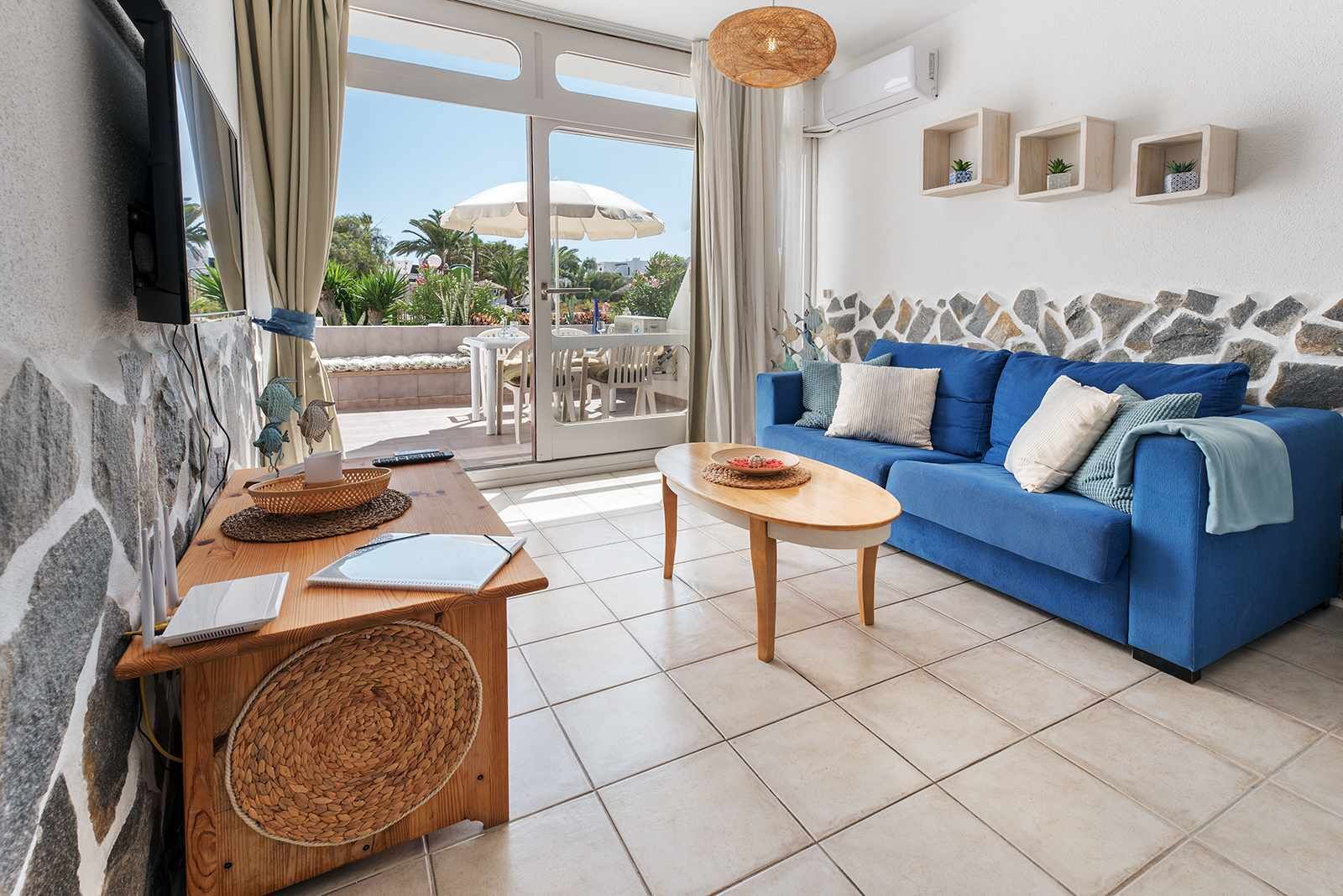 A living room with a blue sofa, a wooden coffee table, and a stone accent wall.