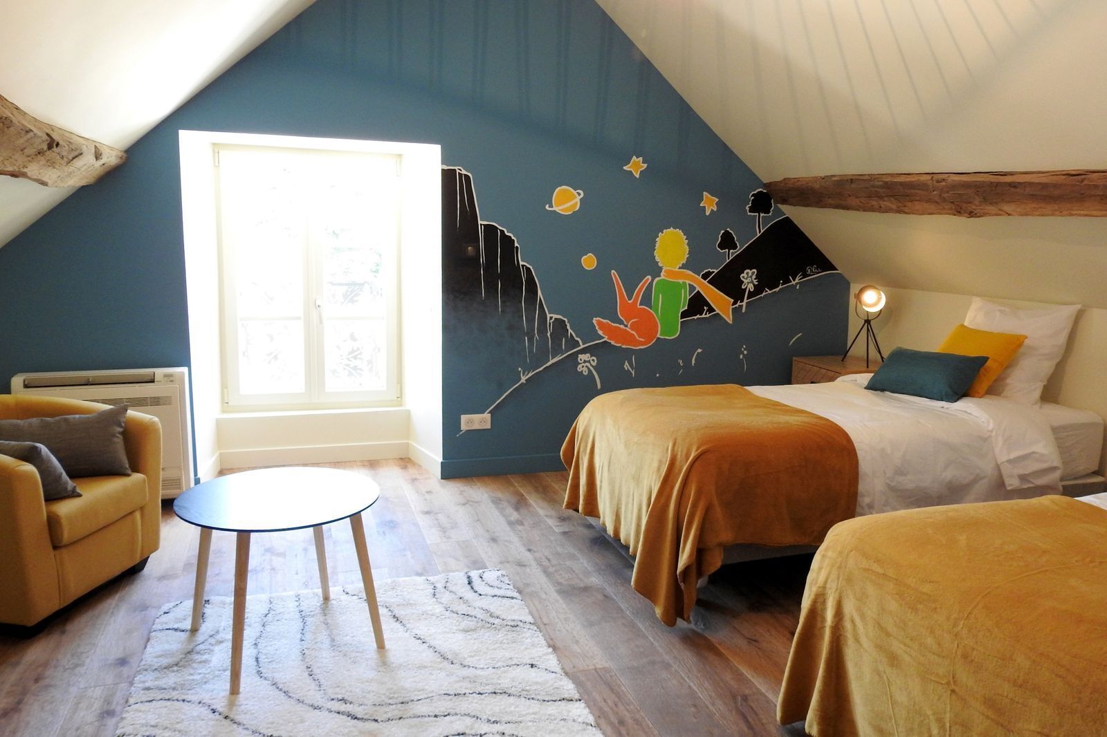 A cozy bedroom with two beds, a small table, and a mural on the wall.