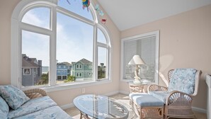 Una habitación con un gran ventanal, muebles de mimbre y vistas a casas de colores.