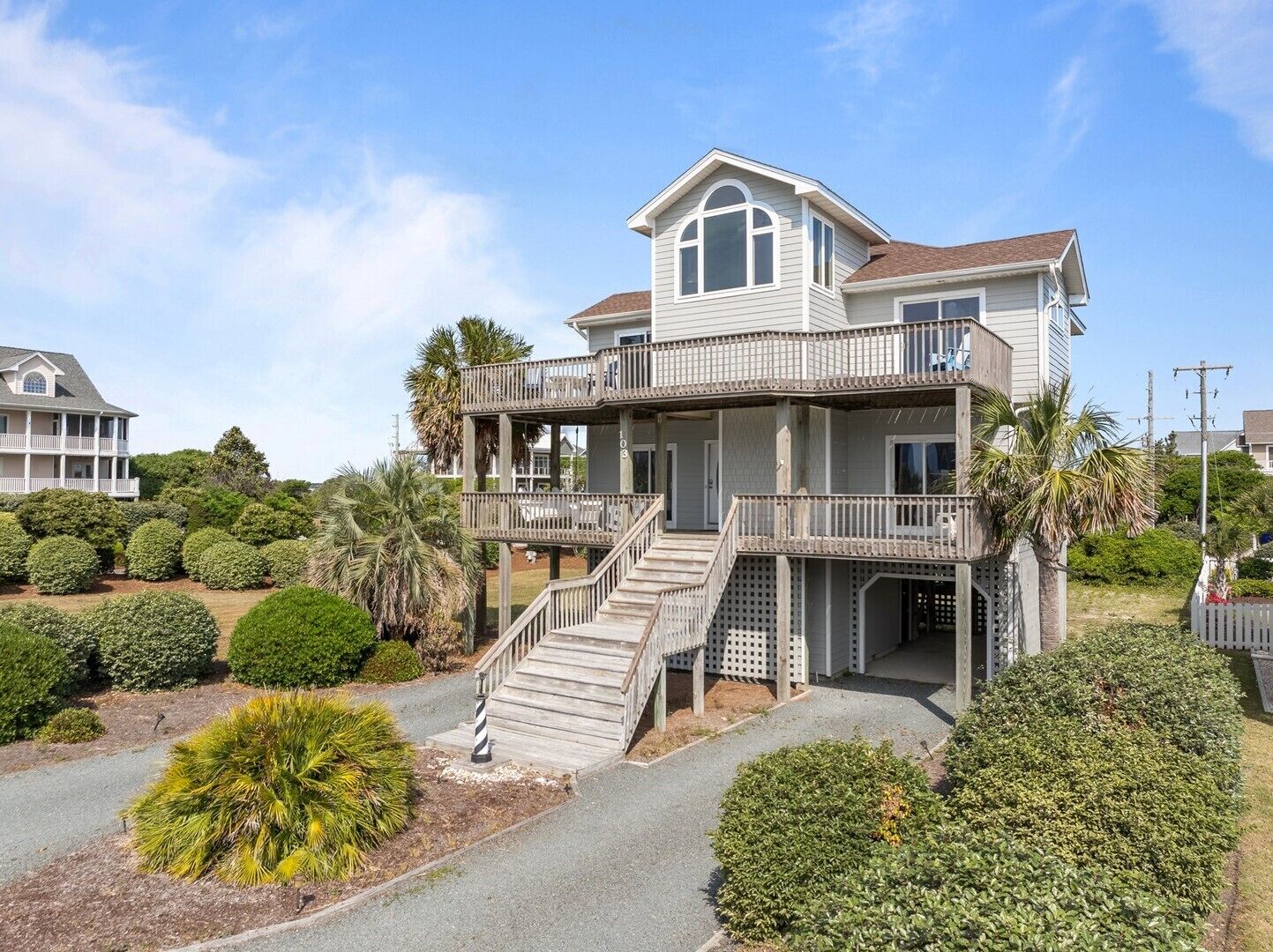 A two-story house with a balcony, a staircase, and a well-maintained garden.