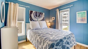 A bedroom with a bed, a window, a radiator, and a view of a balcony. - Oceanfront, 3-bedroom Whale Song in Surf City - perfect for 7 guests. (Surf City)