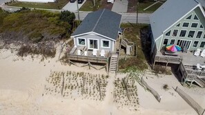 A beachfront property with a large house featuring a covered deck and a separate building with a colorful umbrella. - Oceanfront, 3-bedroom Whale Song in Surf City - perfect for 7 guests. (Surf City)
