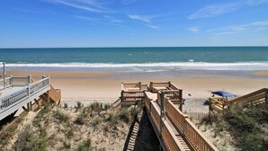 A beach with wooden walkways leading to the shore, a clear blue sky, and calm ocean waves. - C-Breeze: Oceanfront 4BR home in Surf City, NC, sleeps 13 comfortably. (Surf City)