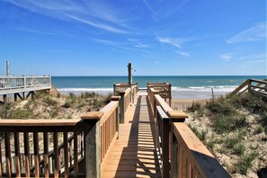 A wooden boardwalk leading to a beach with clear skies.