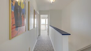 Um corredor com luminária, um apoio azul e obras de arte emolduradas na parede.