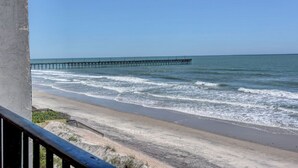 A beach with a pier extending into the ocean, a sandy shoreline, and a clear blue sky. - Oceanfront 3BR Villa Capriani 315B in North Topsail Beach, perfect for families! (N Topsail Beach)