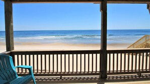 Eine Holzterrasse mit Blick auf Strand und Meer.