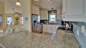 Eine moderne Küche mit Granit Arbeitsplatten, Edelstahlgeräten und weißen Schränken.