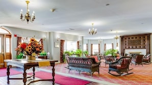 A spacious lobby with a wooden table, wicker chairs, and a floral arrangement. - Originally built in Chautauqua Institution in 1890, the original St. Elmo Hotel building was torn down and rebuilt as a residential condominium.  It now offers the convenience of an elevator (Chautauqua)