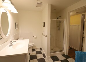 Une salle de bain avec un lavabo blanc, des toilettes et une cabine de douche en verre.