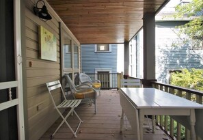 Une véranda abritée avec une table et des chaises, une petite fenêtre et une porte.