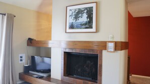 Una sala de estar con chimenea, un televisor sobre un mueble de madera y un cuadro enmarcado en la pared.