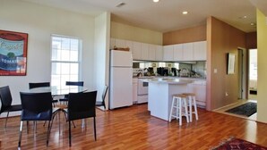 Une cuisine moderne avec des meubles blancs, un îlot central et un coin repas comprenant une table et des chaises.
