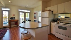 Une cuisine avec un îlot central, un réfrigérateur et une cuisinière. On y trouve une table à manger avec des chaises et une fenêtre donnant sur un beau paysage.