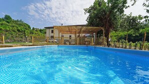 A swimming pool with a tiled floor, surrounded by a wooden fence and a covered area with a roof. - VILLA ADELAIDE 20Pax, Free WiFi, Private pool near Apuan Alps and Cinque Terre (Toscana)