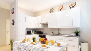 A modern kitchen with white cabinetry, a dining table with chairs, and breakfast items. - Croisette -palais festival-Citycenter -confortable, Croisette - palais festiva l- Citycenter  (Cannes)