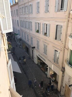 Une rue étroite bordée de bâtiments des deux côtés, où l’on trouve une variété de boutiques et une devanture de magasin bien visible avec une enseigne.