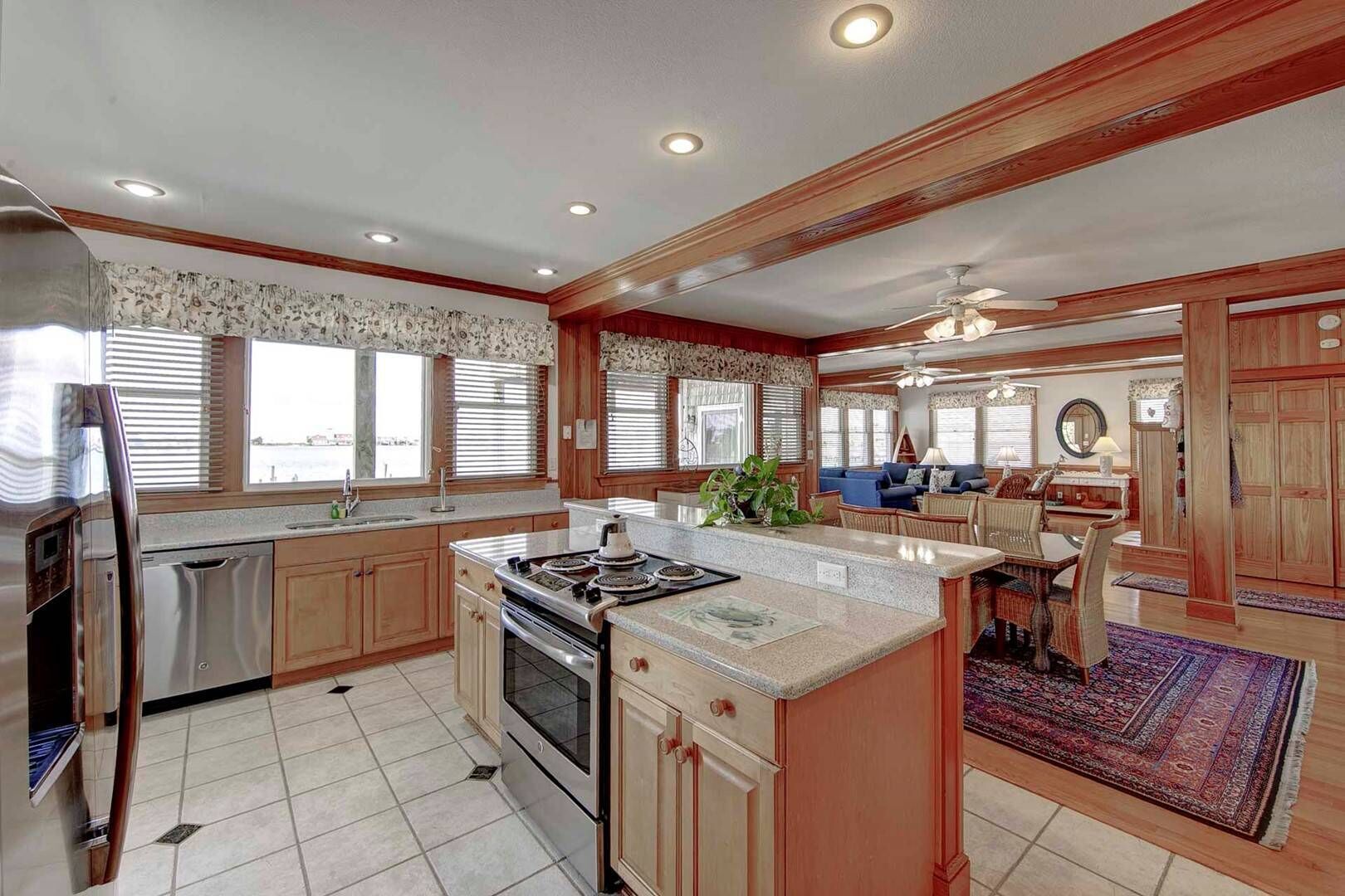 A spacious kitchen with a central island, wooden cabinets, and a dining area with a rug.