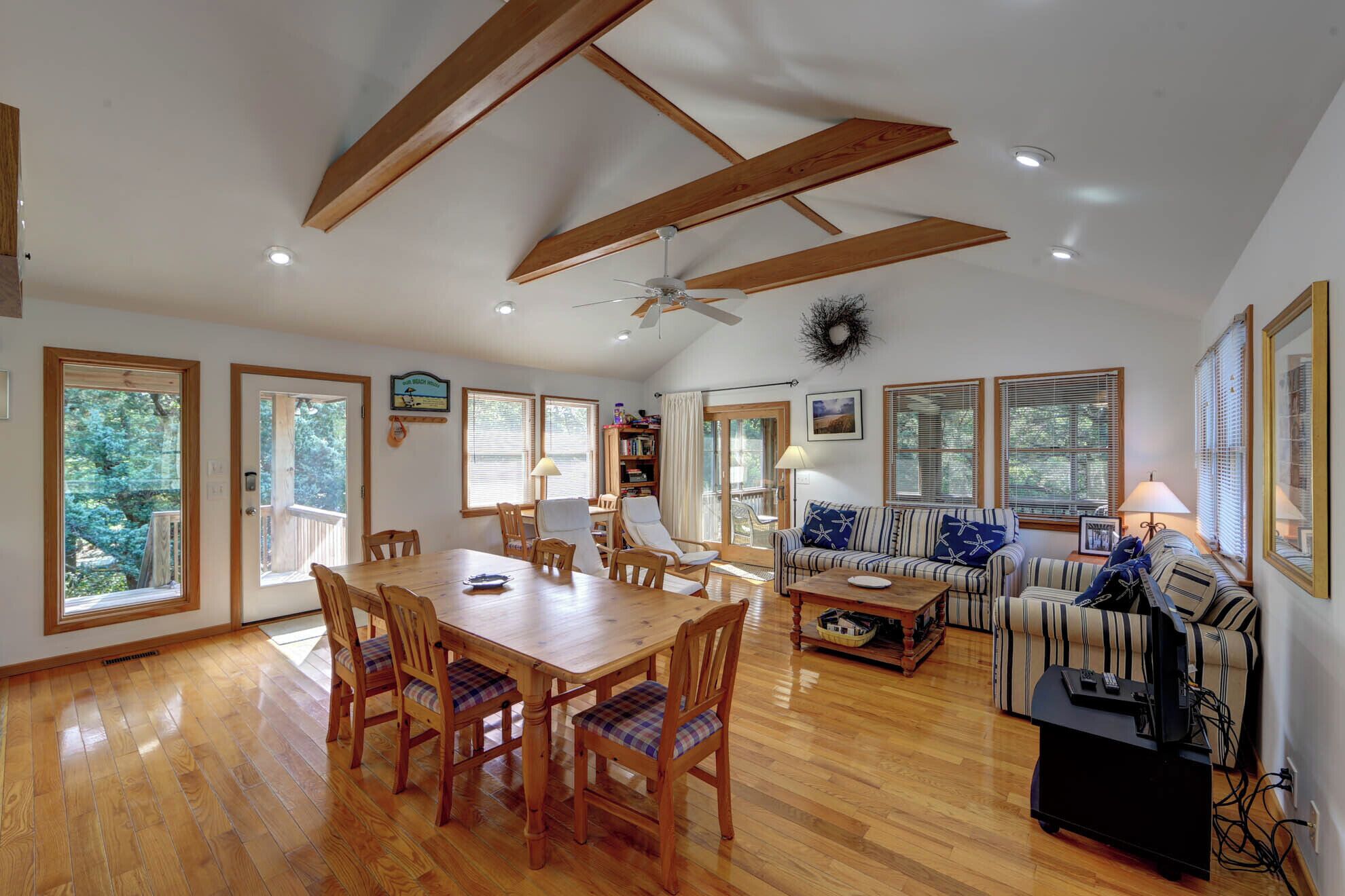 A spacious living room with a wooden dining table, a sofa, and a television.