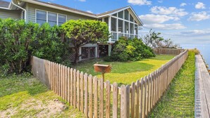 A house with a large front yard, a wooden fence, and a view of the water. - Chai Tide - Ocracoke Island (Ocracoke)