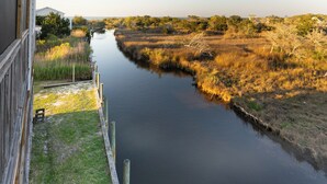 Ein Fluss mit grünen Ufern, einer Holzsteganlage und einem Gebäude im Hintergrund.