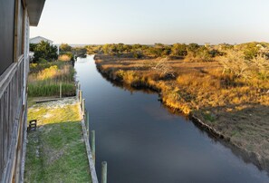 A river with grassy banks, a wooden dock, and a building in the background.