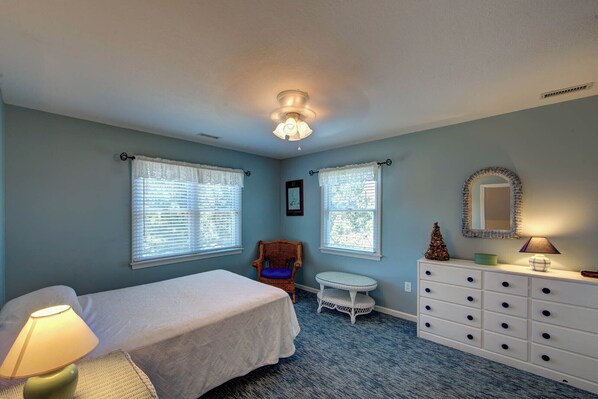 A bedroom with two beds, a dresser, a chair, a small table, and a mirror.