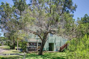 A green wooden building with a covered porch and a staircase leading to the entrance. - Widgeon's Rest - Ocracoke Island (Ocracoke)
