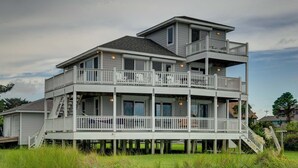 A multi-story waterfront house with a balcony, a covered deck, and a stairway leading to the upper levels. - Blue Oyster - Ocracoke Island (Ocracoke)