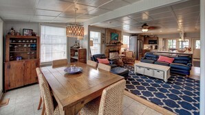 A spacious living room with a wooden dining table, comfortable seating, and a fireplace. - Fig and Thistle - Ocracoke Island (Ocracoke)