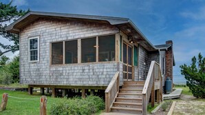 A wooden cabin with a large window, a staircase, and a small deck. - Fig and Thistle - Ocracoke Island (Ocracoke)