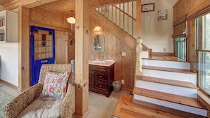 A wooden interior with a blue door, a staircase, and a wicker chair.