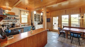 A wooden interior with a kitchen area, dining table, and chairs.
