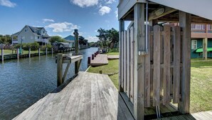 A waterfront property with a wooden dock leading to a house with a balcony. - The Dory - Ocracoke Island (Ocracoke)