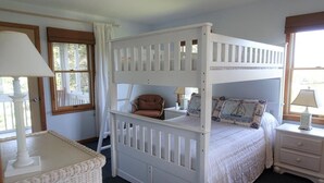 Habitación con literas, una silla y una mesita de noche.