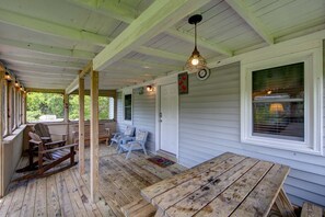 Relax on the covered porch with a rocking chair, Adirondack chairs, and a wooden table.